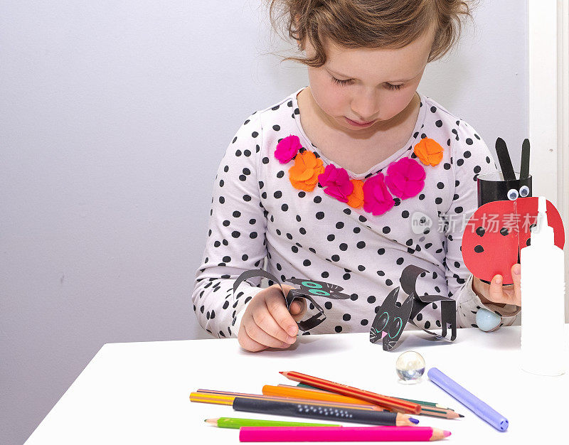 一个5岁的金发白种人女孩在用纸做工艺品。