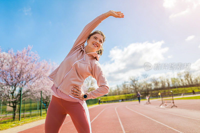 运动的年轻女子在跑道上热身。