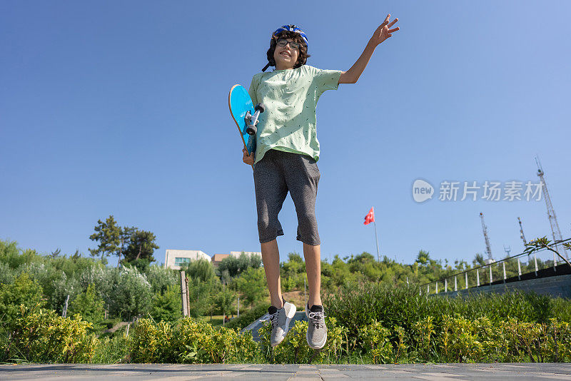 年轻的滑板手用滑板跳跃。