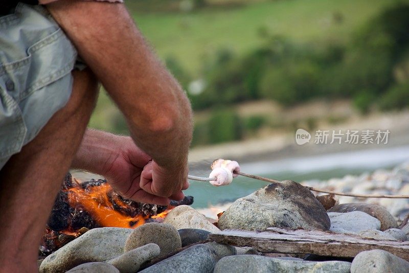 男人在篝火上煮棉花糖