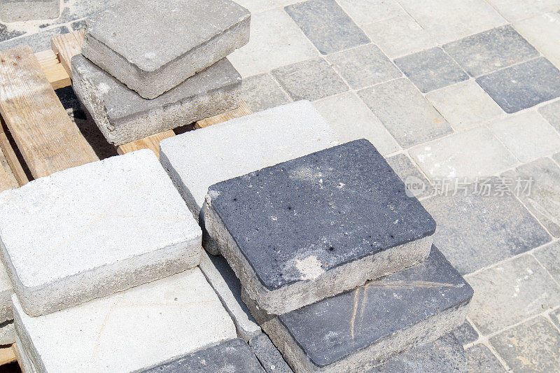 堆放在托盘上的混凝土或铺好的灰色铺路板或地板或人行道上的石头。混凝土铺路板或在后院铺路。花园的砖路在庭院的沙质基础上。