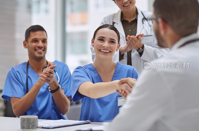在一家医院的会议室里，一群医生在会议中握手并鼓掌