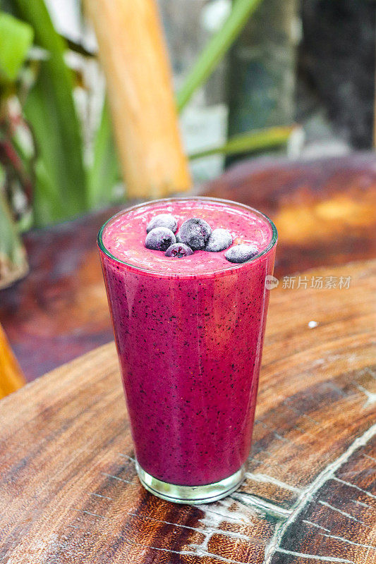 粉红色Açaí浆果冰沙果汁与蓝莓健康排毒饮料在热带花园