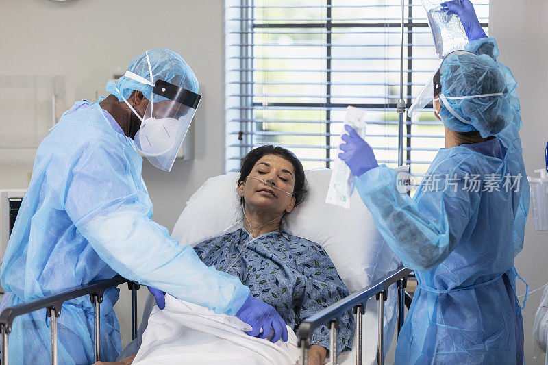 穿戴个人防护装备的医护人员和躺在病床上的病人