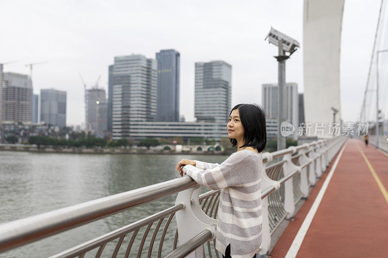 在市中心的一座桥上，一位亚洲妇女望着远方