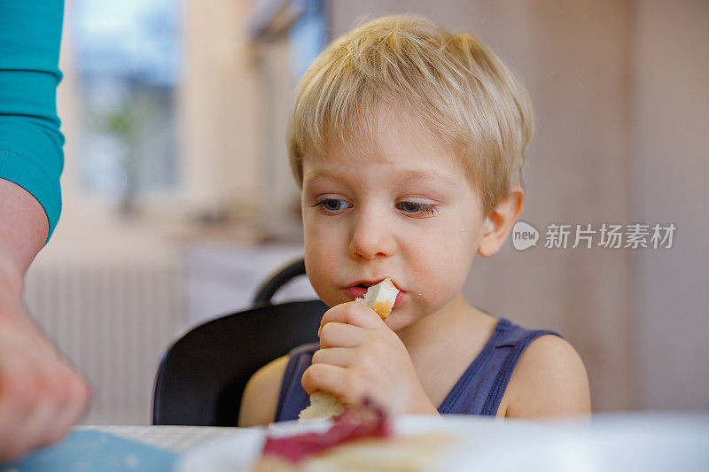 金发幼童咬着切片面包，在家独立吃饭