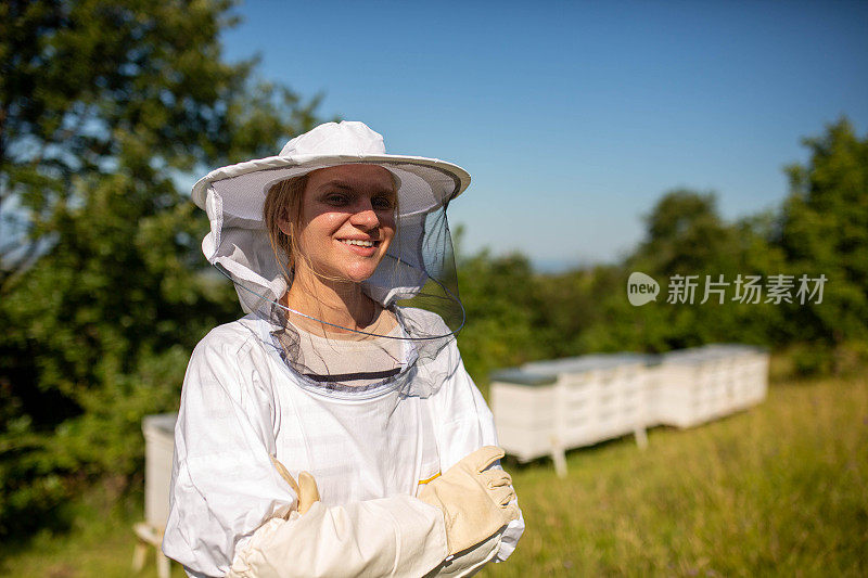 一名女性养蜂人在蜂箱前穿着防护服的肖像