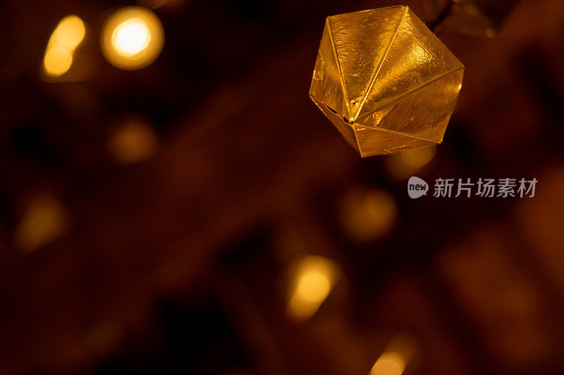 一颗金色钻石的低角度细节悬挂在granollers门廊的木质天花板上，随后是两颗以上的钻石