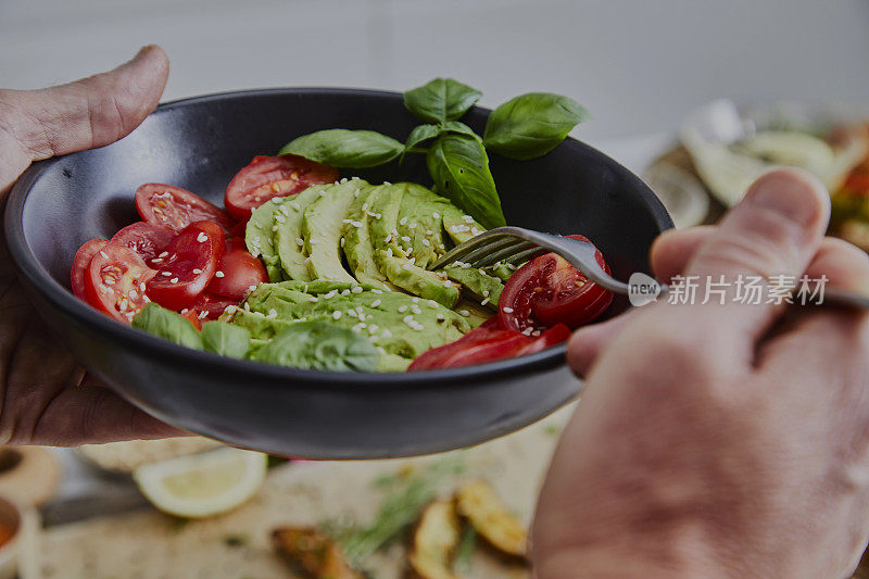 一个男人正在用陶瓷盘子吃素食沙拉