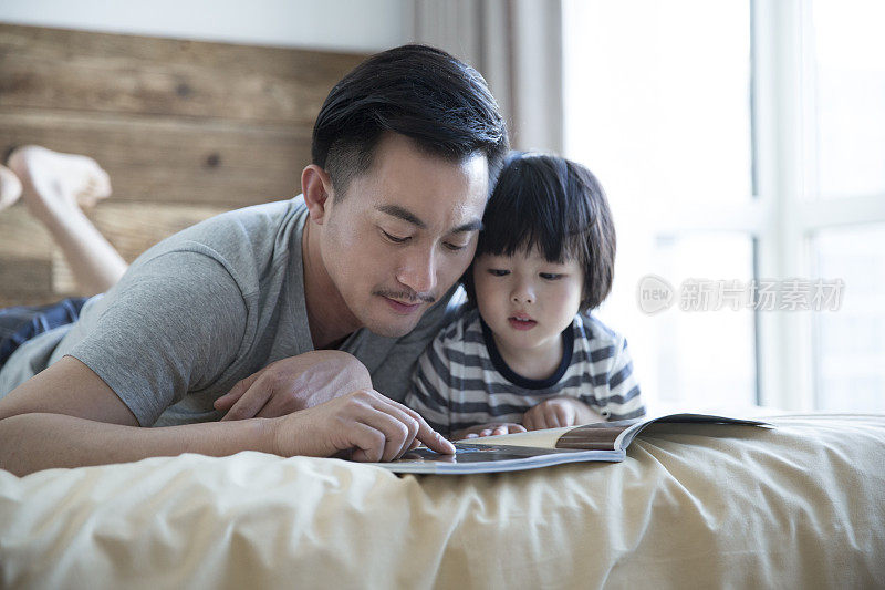 父亲陪着孩子在卧室里给儿子读故事——库存照片