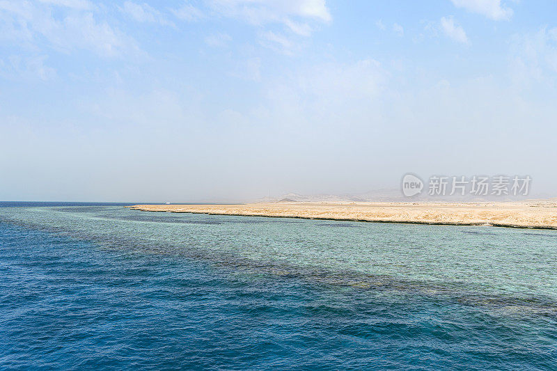 蓝天白云碧水。海滩在地平线上。埃及沙姆沙伊赫的海岸线，海水清澈