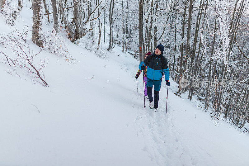 年轻的男性徒步旅行者和他的女性朋友一起在雪山上远足