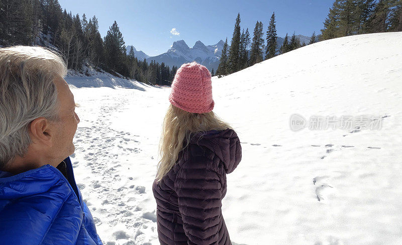 成熟的夫妇走在雪山小路上