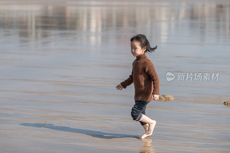 一个亚洲女孩赤脚在沙滩上奔跑
