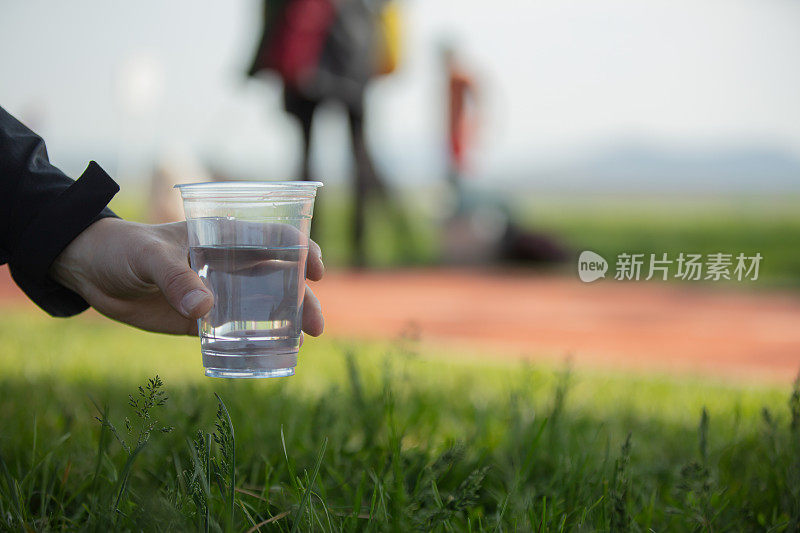 年轻人拿着一个塑料杯。