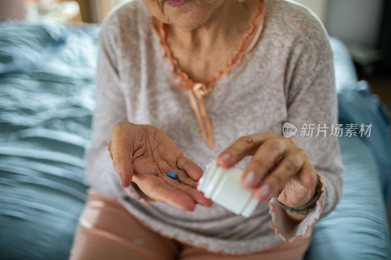 老女人在卧室里从药瓶里拿药