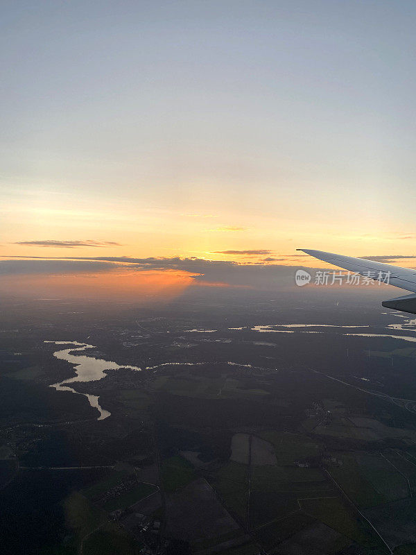 在接近德国柏林勃兰登堡机场时，透过飞机窗户看到美丽的日落。