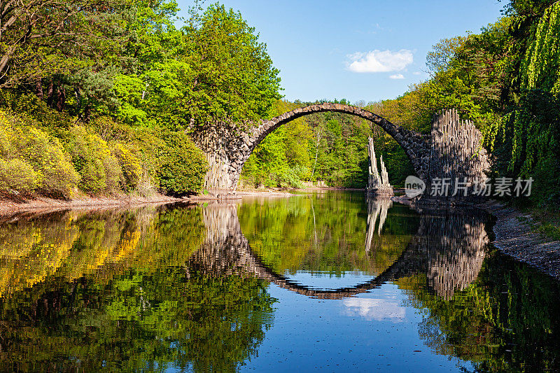 德国克罗姆劳的拱桥(Rakotzbrucke，魔鬼桥)在平静的水面上的倒影