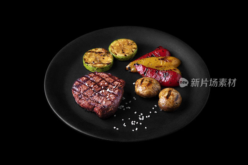 烤猪肉牛排配蘑菇，西葫芦，胡椒和盐，黑色背景