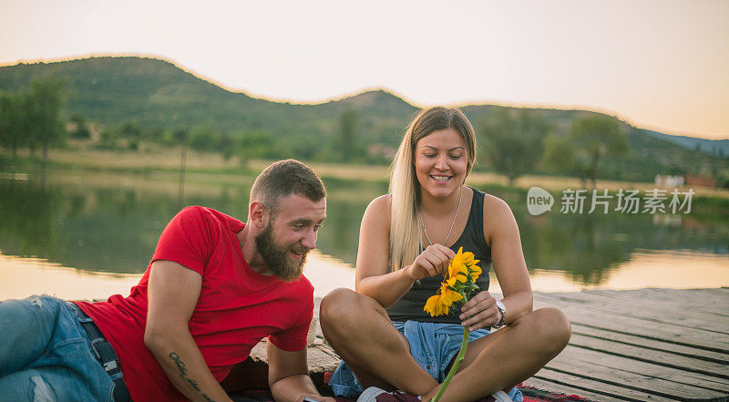 年轻夫妇坐在湖边码头欣赏日落