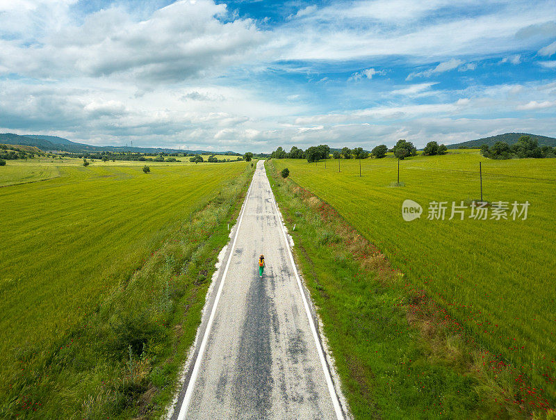 春天里，年轻的背包旅行者女孩走在美丽的乡间小路上