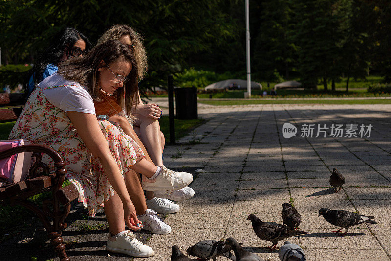 一个女人把爆米花给鸽子吃。