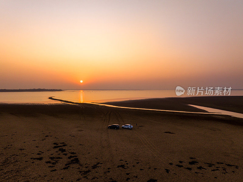 夕阳下的湖，汽车停在沙滩上