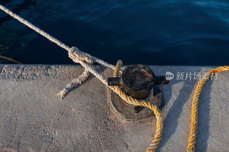 日落时分，一艘游艇用一根绳子系在港口的系柱上。在码头停一下。锚和刹车概念
