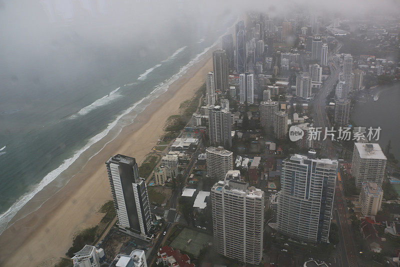 在一个风雨交加的下午，从高观测点的窗户向南观看沿着黄金海岸的阔滩城市景观