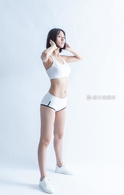 一个穿着运动服的年轻亚洲女子正在摄影棚里摆姿势