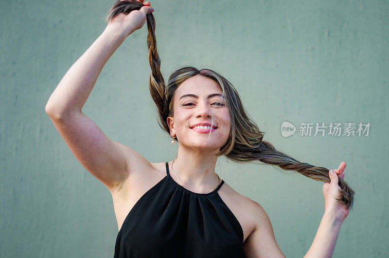 美丽的年轻女子的肖像玩她的头发在灰色背景