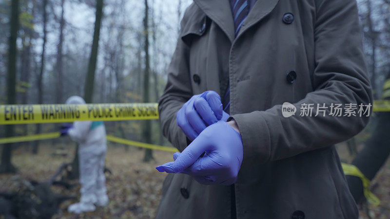 调查员戴上手套，法医小组在犯罪现场的胶带后面工作