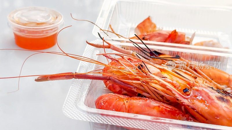 透明的外卖盒里装着丰满的烤对虾，配上浓郁的蘸酱