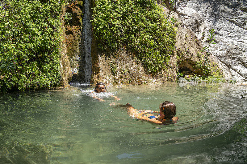 在瀑布中漂浮的女人。奥卢德尼兹卡巴克湾的阿拉德尔瀑布。Fethiye,土耳其。