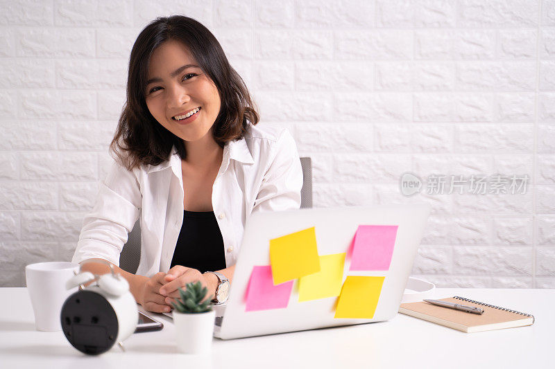 一个快乐的女人坐在家里的办公室里用笔记本电脑工作