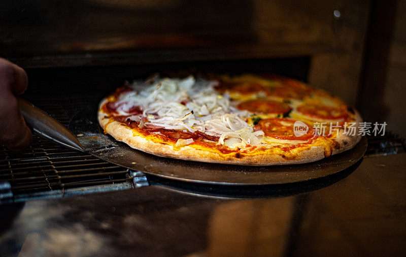 披萨店将披萨从电炉中拿出，有玛格丽塔和卡拉布雷萨的味道