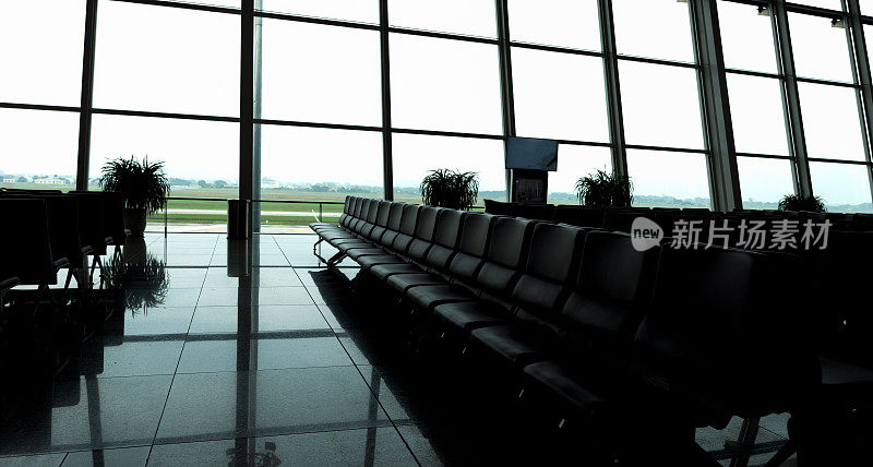 机场等待登机的乘客沙发剪影，日出的背景