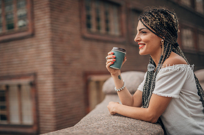 一个年轻女人在市中心的大街上喝咖啡休息
