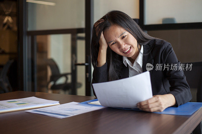 亚洲女商人感到担心和沮丧的销售报告在办公室