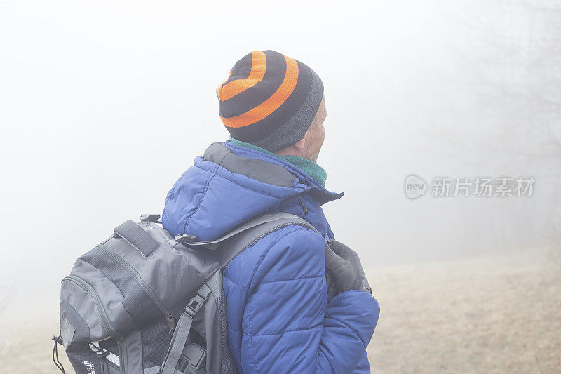 一名成年男子在寒冷多雾的日子徒步旅行