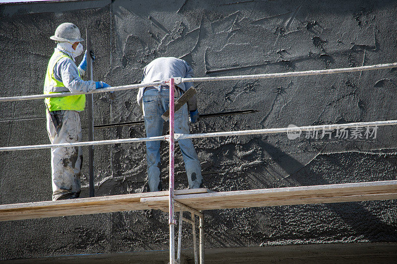 一位建筑工人在雪莉大道9123号的工地上向墙上喷洒混凝土