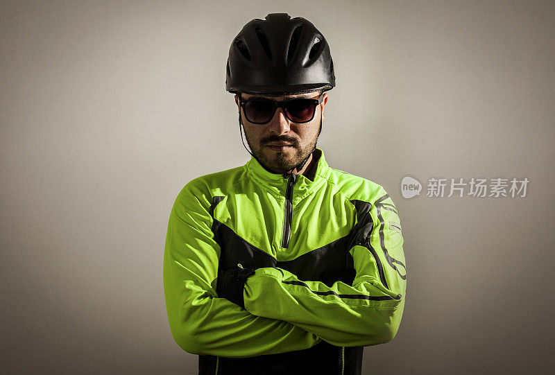 年轻的男性骑自行车面对镜头，双臂交叉