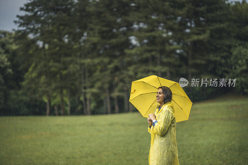 快乐的女人微笑着行走在雨天