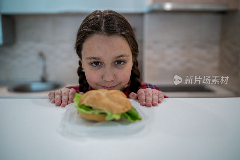 十几岁的女孩看着开胃的汉堡躺在她面前的桌子上