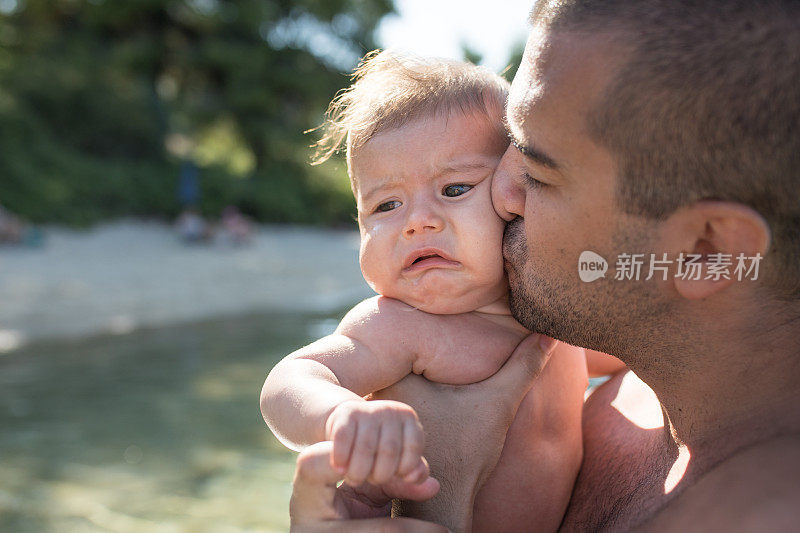 父亲抱着并亲吻一个哭泣的婴儿