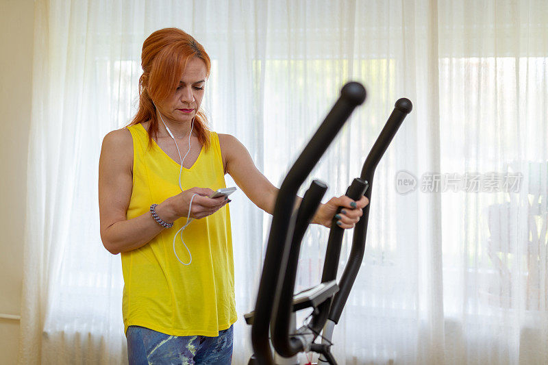 一个女人在手机上制作播放列表，准备在客厅里开始锻炼