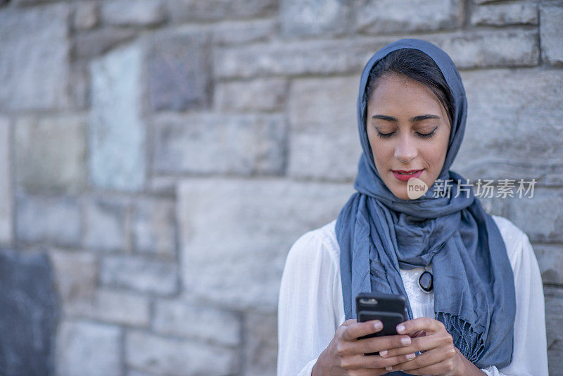 年轻的穆斯林女性在用她的智能手机