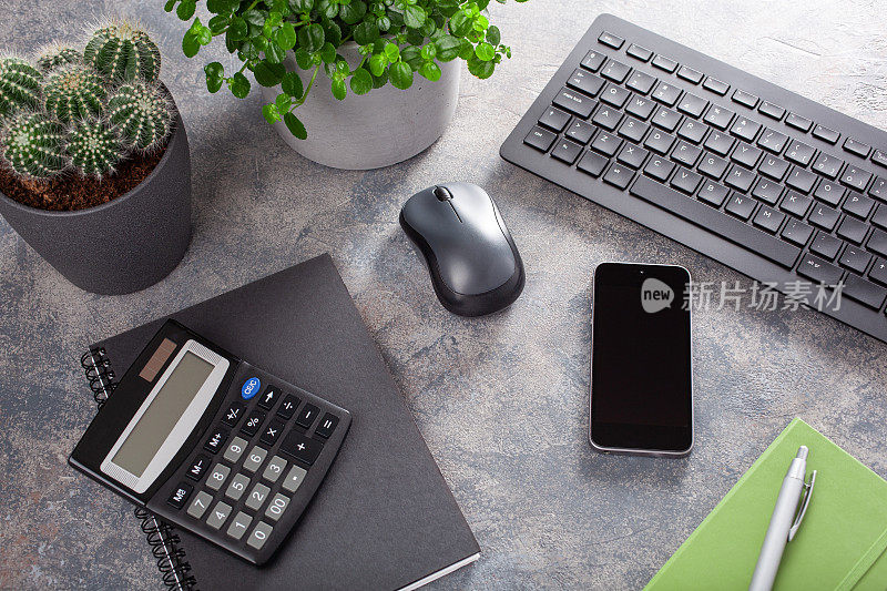 家庭办公书桌与键盘电脑智能手机笔记本室内植物，工作空间在家