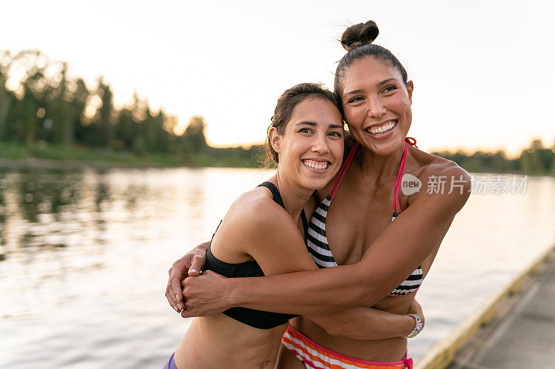 混合种族太平洋岛民妇女在日落时拥抱，而在湖边一起