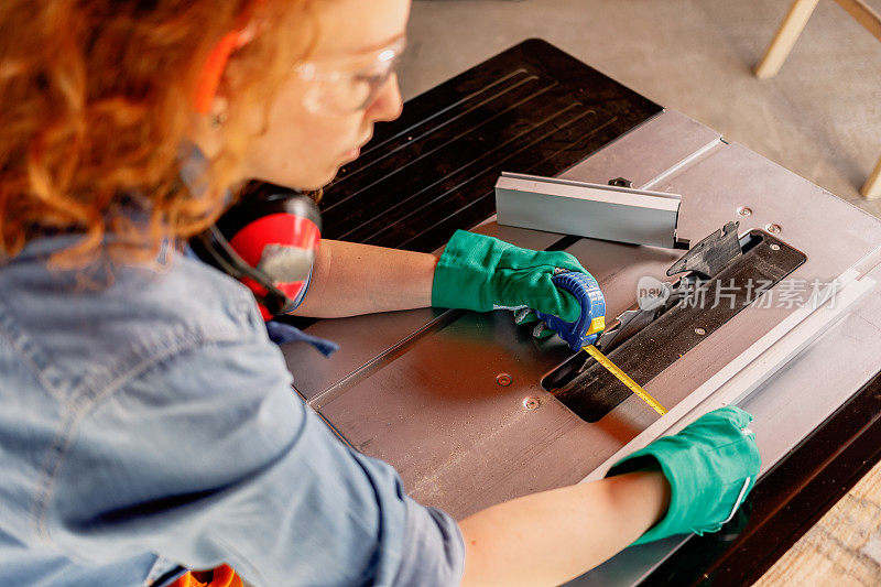 年轻的女木匠在人字锯上测量木板的宽度